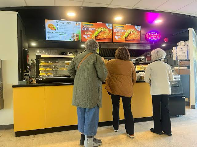 Customers at the Stuff It Up counter beneath digital menu boards